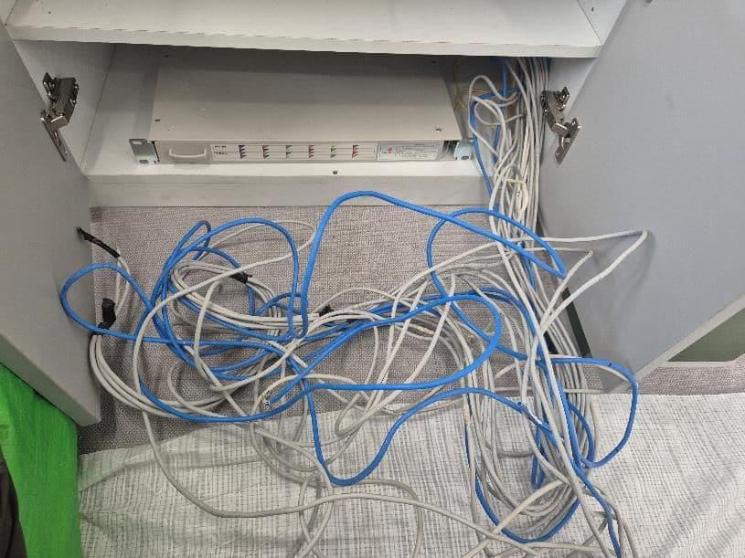 공사 전 카운터 장 안, 파란색과 흰색 랜선이 묶이지 않은 채 바닥에 뭉쳐 있고 위쪽에 단자대만 붙어 있다